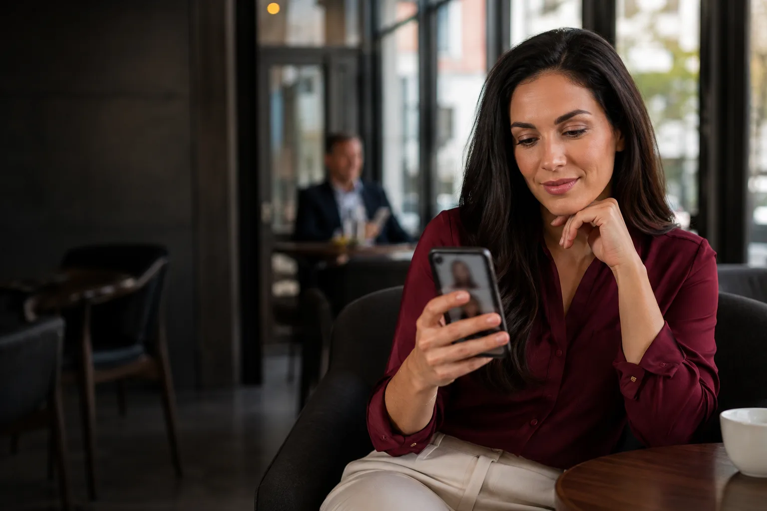 Adult woman browsing local dating profiles on her phone in a contemporary cafe
